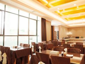 a restaurant with tables and chairs and a large window at Vienna Hotel Ganzhou Anyuan in Tieshan