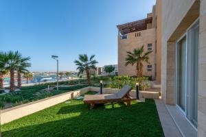 a patio with a bench and palm trees and a building at Golden Apartments El Gouna in Hurghada
