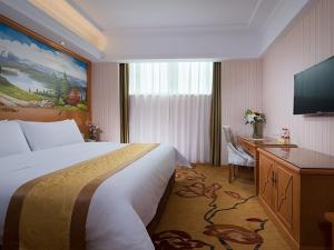 ShengzhouにあるVienna Hotel (Shengzhou Bada Hotel)のベッド1台、薄型テレビが備わるホテルルームです。