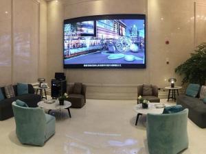a lobby with couches and tables and a large tv at Vienna International Hotel Jieyang People's Avenue in Jieyang