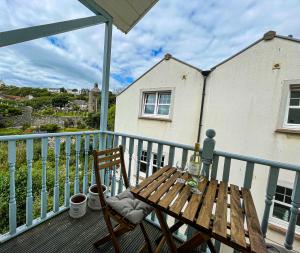 uma mesa de madeira e cadeira sentadas numa varanda em Harbourside Apartments em Portpatrick