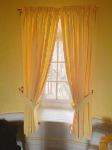 ein Fenster mit gelben Vorhängen in einem Zimmer in der Unterkunft B&B Chateau de Villersexel in Villersexel