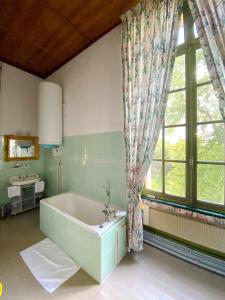a bathroom with a tub and a large window at B&B Chateau de Villersexel in Villersexel