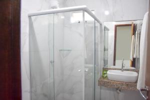 y baño con ducha acristalada y lavamanos. en Duna´s guest house en Salvador