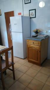 a kitchen with a white refrigerator and a table at Casa das Lezírias in Unhais da Serra