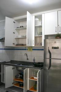 une cuisine avec des armoires blanches et un réfrigérateur en acier inoxydable dans l'établissement Apto 105 - Edifício Imola - Conforto e Segurança para sua família, à Ubatuba