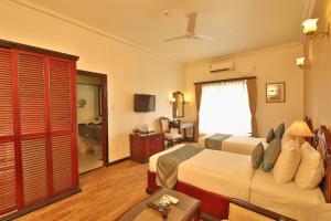 a hotel room with two beds and a television at The Lindsay in Kolkata