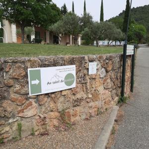 um sinal numa parede de pedra ao lado de uma rua em Chambres & Table d'Hôtes Au Soleil du Bonheur em Lafare