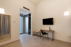 Habitación con escritorio y TV en la pared. en Baglio Custera en Marsala