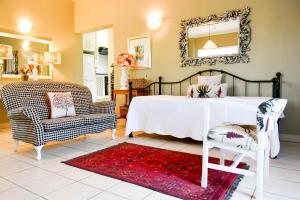 a bedroom with a bed and a chair and a mirror at Bella's B&B in Vryheid