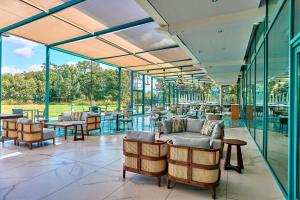 馬洛的住宿－皇冠假日馬洛酒店，餐厅设有玻璃墙和桌椅
