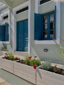 a house with blue shutters and flowers in a garden at 1890 Fanourakis House in Halki