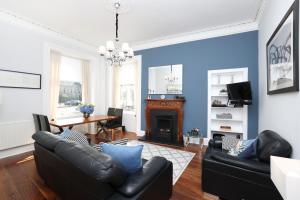 een woonkamer met een zwarte bank en een tafel bij ALTIDO Stunning Ground-floor 2 Bedroom New Town Apartment in Edinburgh