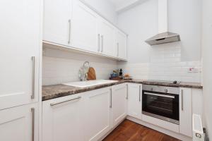 a white kitchen with white cabinets and a sink at ALTIDO Stunning Ground-floor 2 Bedroom New Town Apartment in Edinburgh