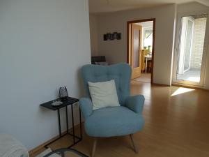 ein Wohnzimmer mit einem blauen Stuhl und einem Tisch in der Unterkunft Ferienwohnung am Lippesee in Paderborn