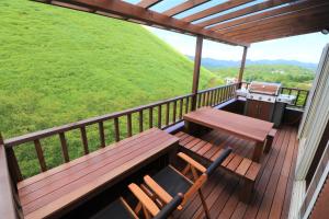 a deck with a bench and a table and chairs at スマートステイ大室山3合目 in Futo