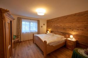 a bedroom with a large bed and a wooden wall at Saukaserstub'n Apartments - Ferienwohnung Schützkogel in Jochberg