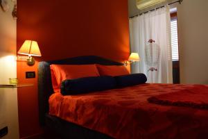 a bedroom with a bed with orange walls and two lamps at B&B Le Casette Di L&ugrave; in Agrigento