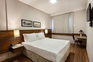 a hotel room with a bed and a chair at Bourbon Londrina Hotel in Londrina