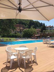 uma mesa e cadeiras debaixo de um guarda-sol ao lado de uma piscina em ENJOY VARENNA CASA VACANZE em Varenna