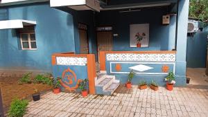 una casa blu con piante in vaso davanti di Thyme Guest House a Palolem
