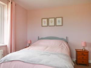a bedroom with a bed with two pink lamps at Driftwood in Penzance