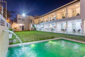 a house with a swimming pool and a fountain at Quinta do Mar Flats Porto de Galinhas in Porto De Galinhas
