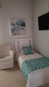 a small bedroom with two beds and a chair at Pousada Marilia in Cabo Frio