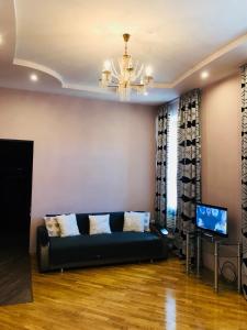 uma sala de estar com um sofá preto e um lustre em Iren Lviv apartment em Lviv