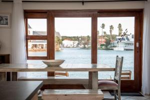 mesa de comedor con vistas al agua en The Marina House, en Jeffreys Bay