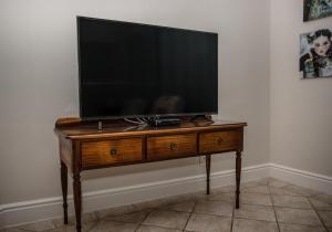 TV de pantalla plana sobre una mesa de madera en The Marina House, en Jeffreys Bay