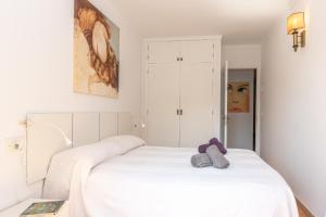 a bedroom with a white bed with a teddy bear on it at Apartment Almirall in Puerto Pollensa By homevillas360 in Pollença +10 photos