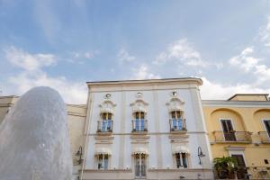 ein weißes Gebäude mit einem Brunnen davor in der Unterkunft IL Borgo Relais in Gravina in Puglia