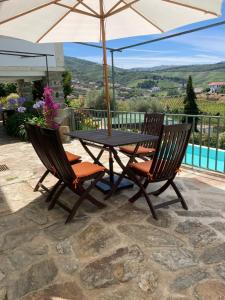 a table and two chairs with an umbrella on a patio at Quinta da Travessa - Douro in Covelinhas
