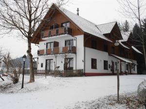 un grand bâtiment avec de la neige au sol dans l'établissement Gasthof Grüner Baum "Kongo", à Amtzell