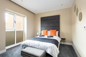 a bedroom with a large bed with orange pillows at For Work Trips - Quiet & Ready to Go - Apartment 1 in Gillingham