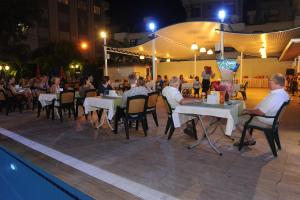 a group of people sitting at tables near a pool at Perle Apart Hotel in Alanya