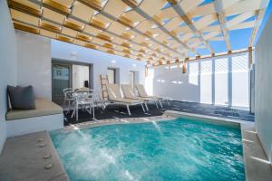 a pool in a room with a table and chairs at Symphony Suites Santorini in Pyrgos
