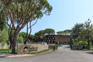 une route menant à un bâtiment avec un mur en pierre dans l'établissement Bellevue Hotel & Resort, à Lido di Jesolo