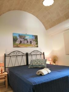una camera da letto con letto nero e copriletto blu di Santa Maria de Lu Trisciulu a Castrignano del Capo