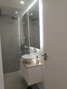 a white bathroom with a sink and a shower at CAIS DE APRESENTAÇÃO NO CORAÇÃO DE AVEIRO in Aveiro +8 photos