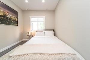 een witte slaapkamer met een groot wit bed. bij Modern Oasis Guest Suite I Walk out Patio I WEM I WiFi! in Edmonton