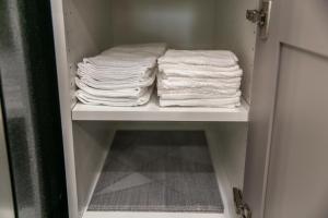 een stapel handdoeken op een plank in een badkamer bij Modern Oasis Guest Suite I Walk out Patio I WEM I WiFi! in Edmonton