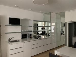 a kitchen with white cabinets and a tv on the wall at Hotel Goldenes Kreuz in Regensburg