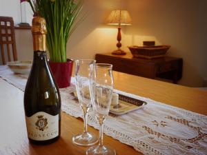 a bottle of wine and three wine glasses on a table at Walwyn Court Barns in Ledbury