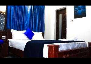 Turavūr的住宿－Shore Beach Homestay，一间卧室配有一张蓝色窗帘的床