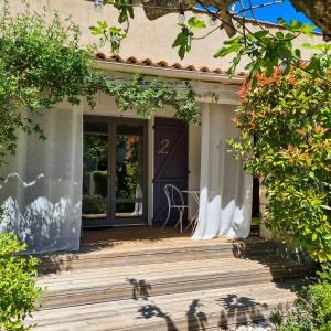 a house with a wooden porch with a door at Hôtel Sous les Figuiers - Piscine, parking, centre ville in Saint-Rémy-de-Provence