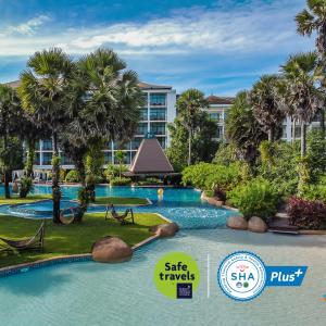 une piscine dans un complexe avec des palmiers et un bâtiment dans l'établissement Naithonburi Beach Resort - SHA Extra Plus, à Nai Thon Beach