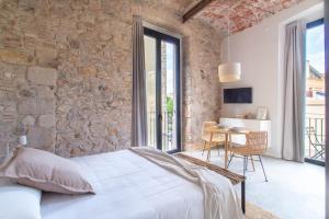 a bedroom with a stone wall and a bed and a table at Caelus Boutique Studio in Girona
