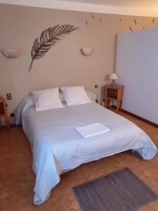 Un dormitorio con una cama blanca con una pluma en la pared en Auberge La Prairie, en Matemale